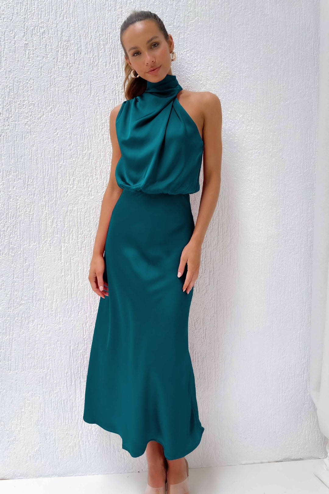 Woman wearing a teal dress against a white background
