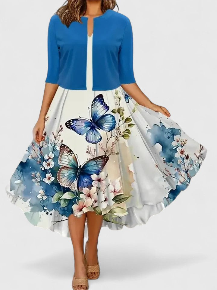 Woman wearing a blue cardigan over a floral dress with butterfly designs on a white background