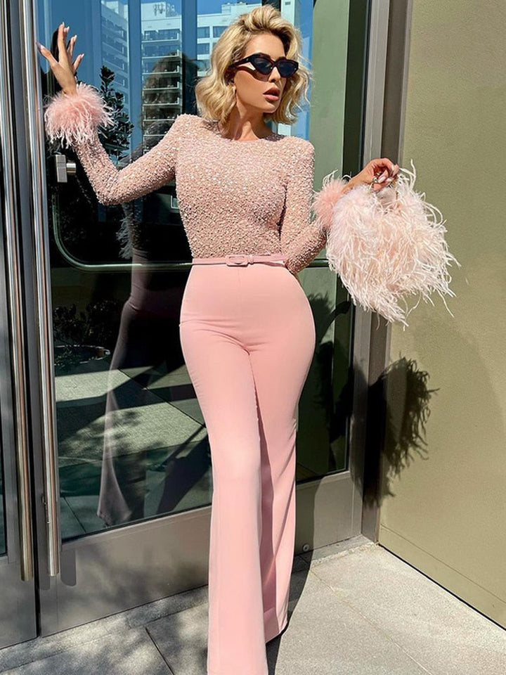Woman in a pink outfit with feathered accessories standing outside a building.