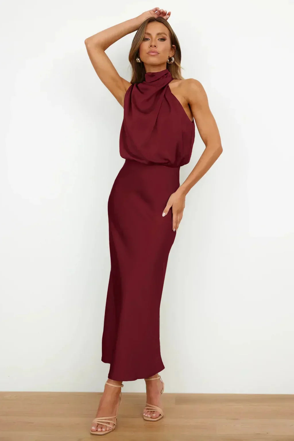 Woman wearing a burgundy halter neck dress against a white background