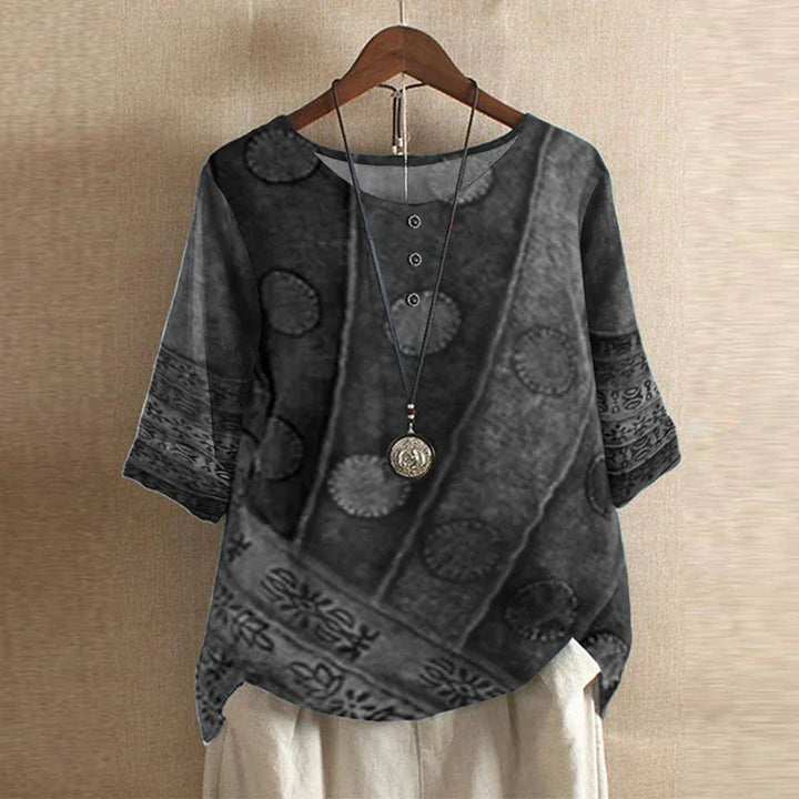 Dark gray textured shirt with circular patterns on a wooden hanger against a beige wall.