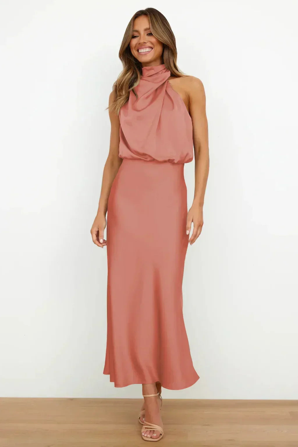 Woman wearing a pink halter neck dress on a white background
