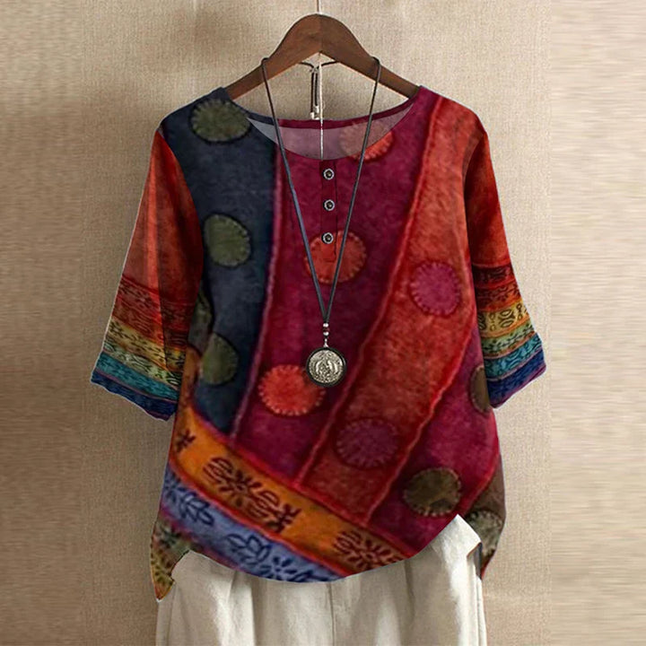 Colorful patterned top on a hanger against a beige wall