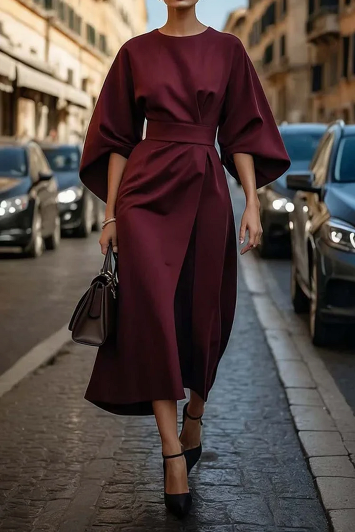Woman in a burgundy dress walking on a city street.