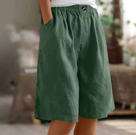 Green shorts worn by a person in an indoor setting with blurred background