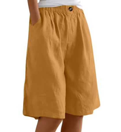 Mustard yellow shorts worn by a person on a white background