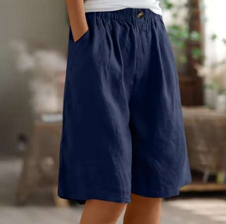Navy blue shorts worn by a person with a blurred indoor background