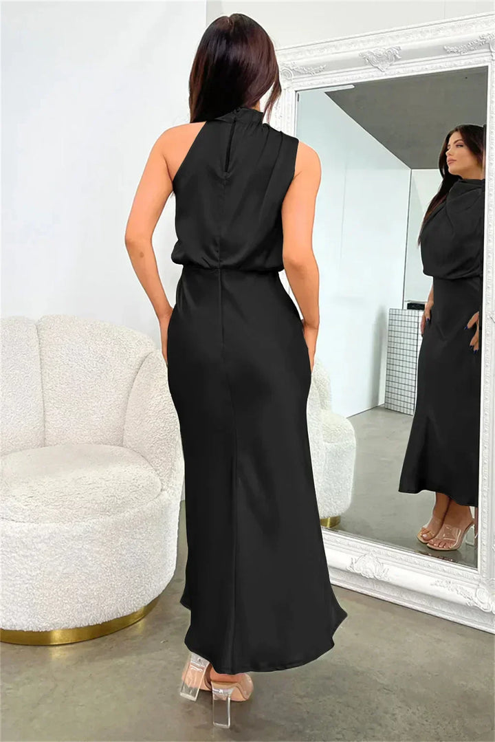 Woman in a black dress standing in front of a mirror in a room with a white armchair.