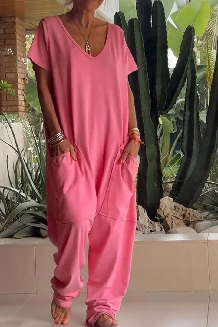 Person wearing a pink jumpsuit standing outdoors with plants in the background