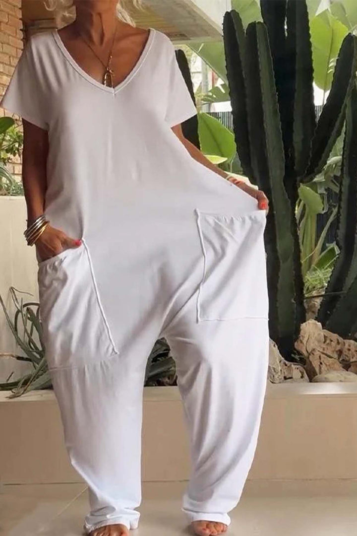 Person wearing a white jumpsuit standing in front of a cactus plant.