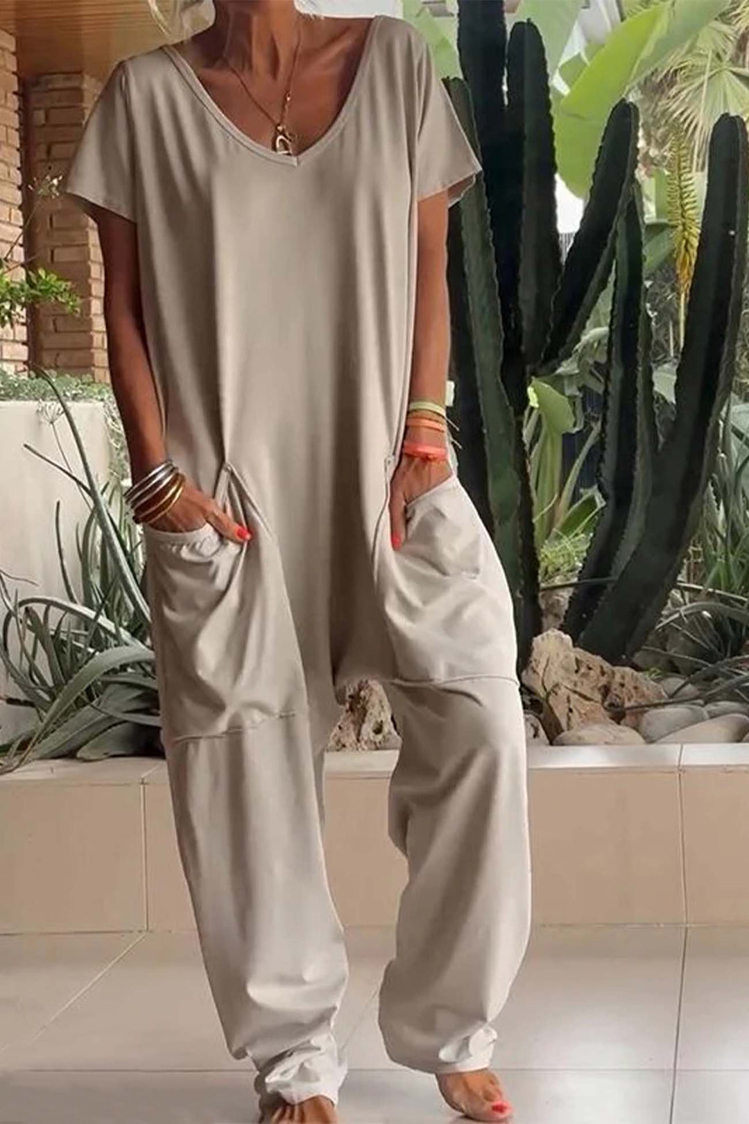 Person wearing a beige jumpsuit with cacti in the background