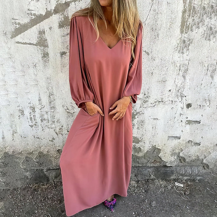 Woman wearing a pink dress against a textured wall.