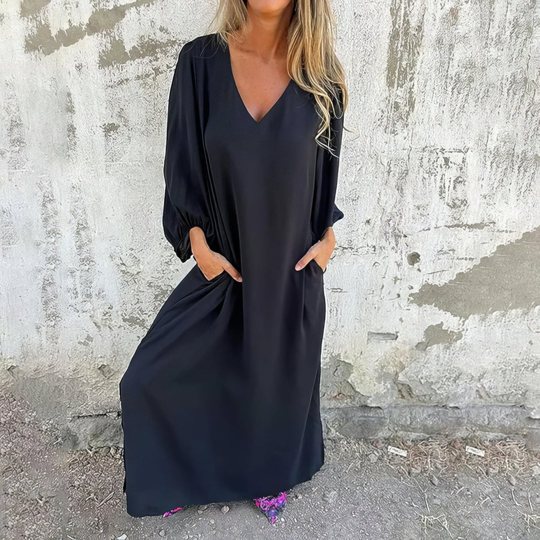 Woman wearing a black dress against a textured wall.