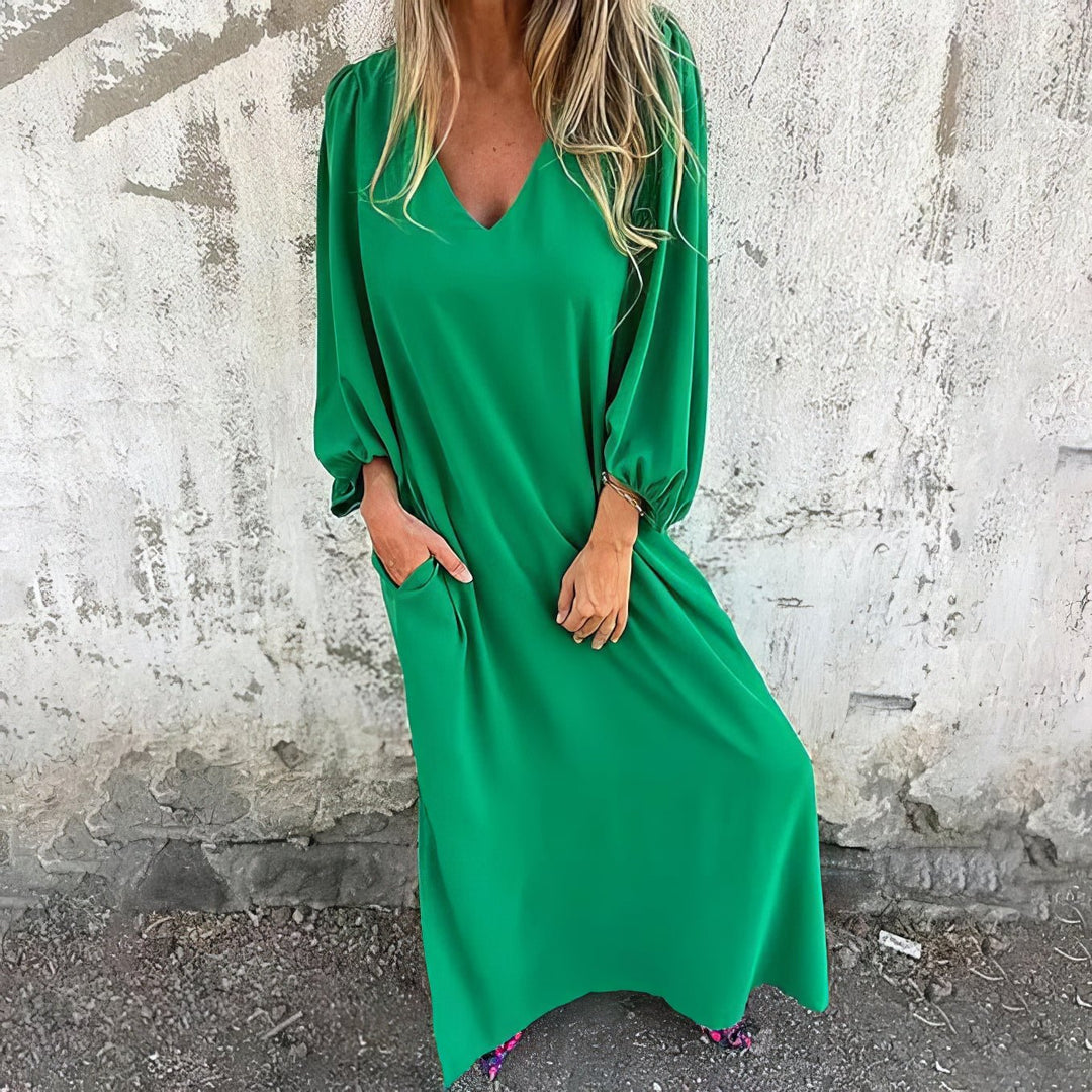 Woman wearing a green dress against a textured wall.