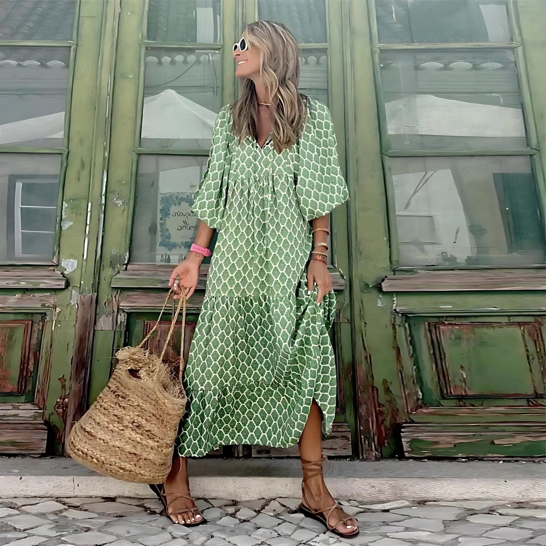 Woman in a green patterned dress standing in front of a green building.