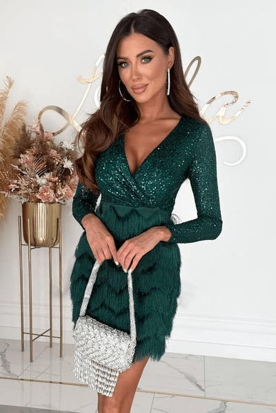 Woman in a green dress holding a silver handbag in a decorated room.