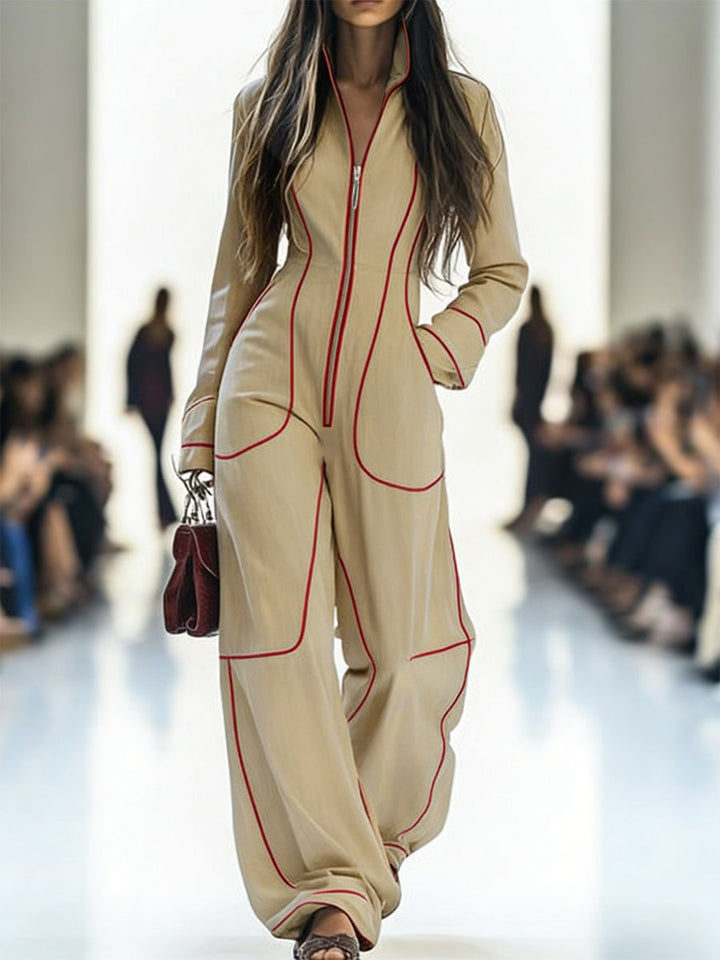 Model walking on a runway wearing a beige outfit with red accents.