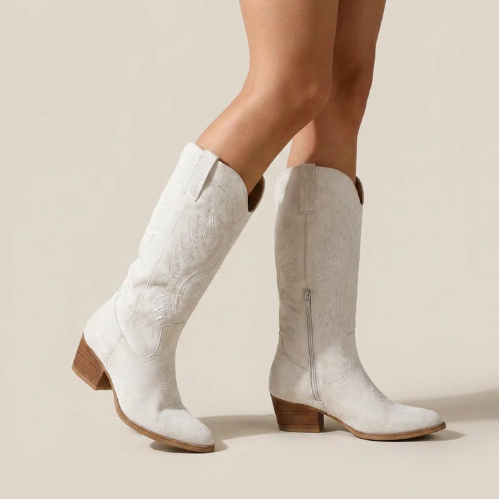 White knee-high boots with brown soles on a neutral background