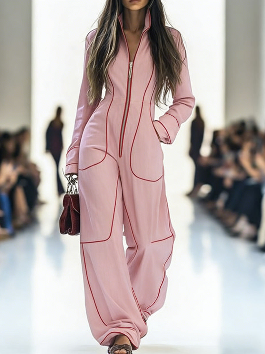 Model wearing a pink outfit with red accents on a runway.