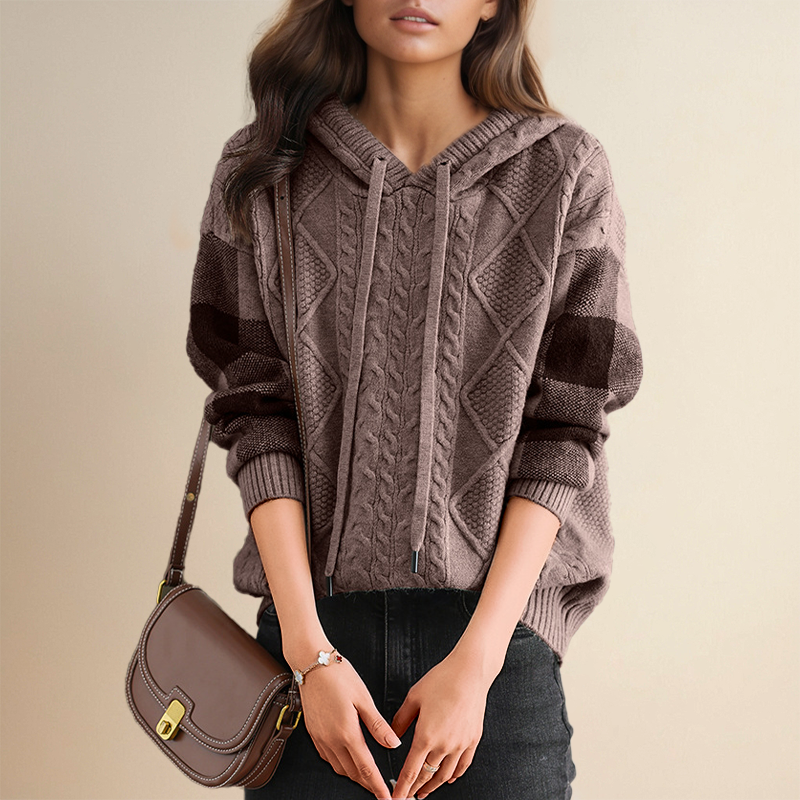 Person wearing a cable knit hoodie with a brown handbag on a beige background
