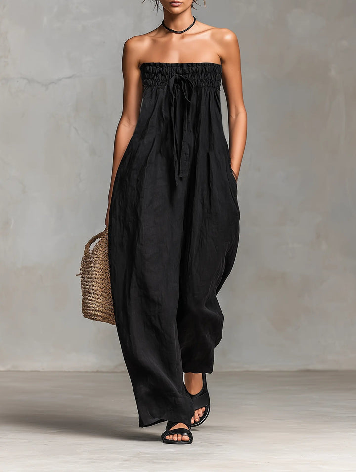 Woman wearing a black strapless jumpsuit against a gray background