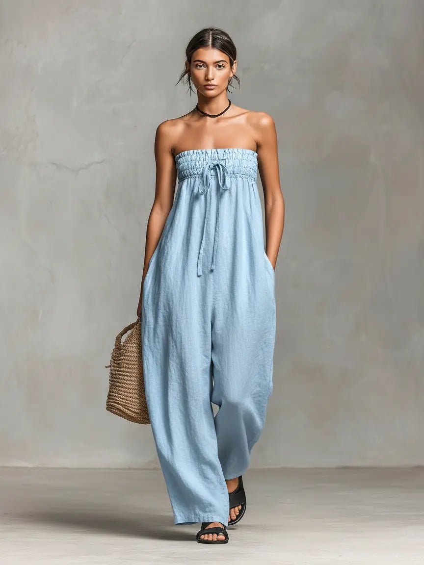 Woman wearing a light blue strapless jumpsuit against a gray background
