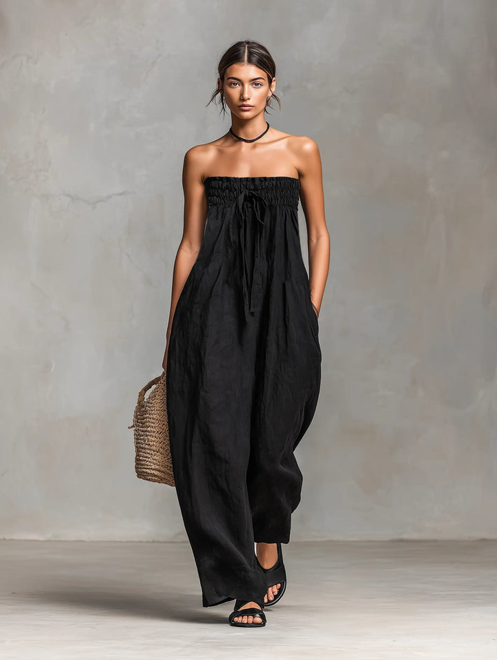 Woman wearing a black strapless jumpsuit against a gray background
