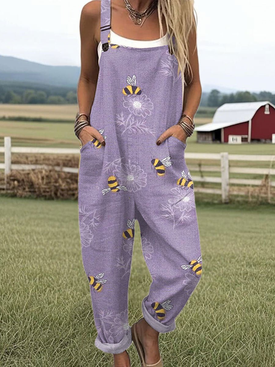 Person wearing a purple floral and bee-patterned jumpsuit in a rural setting with a red barn.