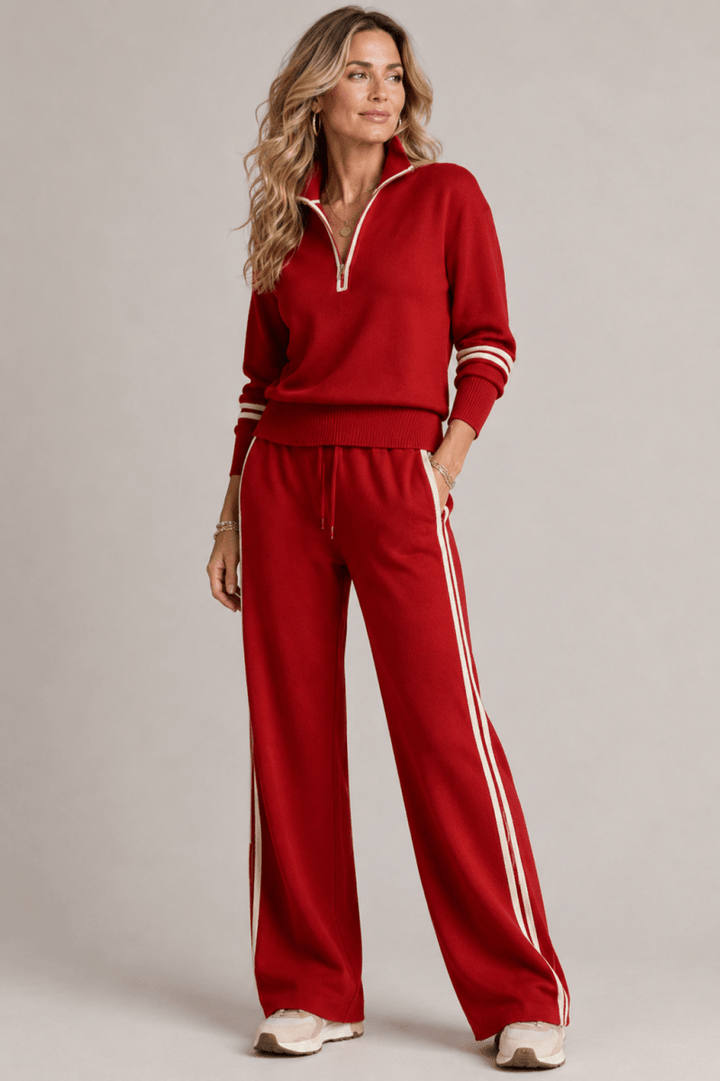 Woman wearing a red tracksuit with white stripes on a plain background