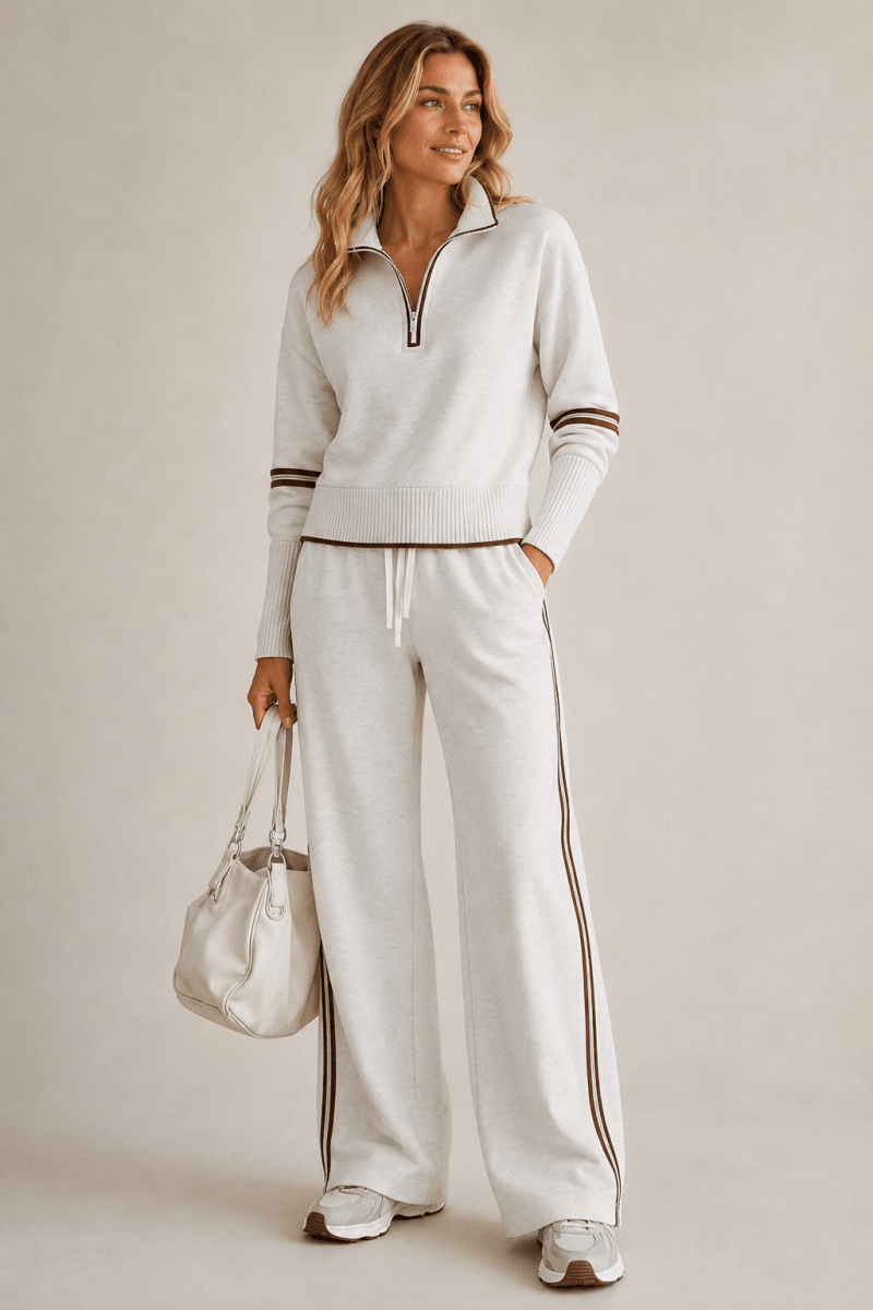 Woman wearing a white tracksuit with brown stripes on a plain background
