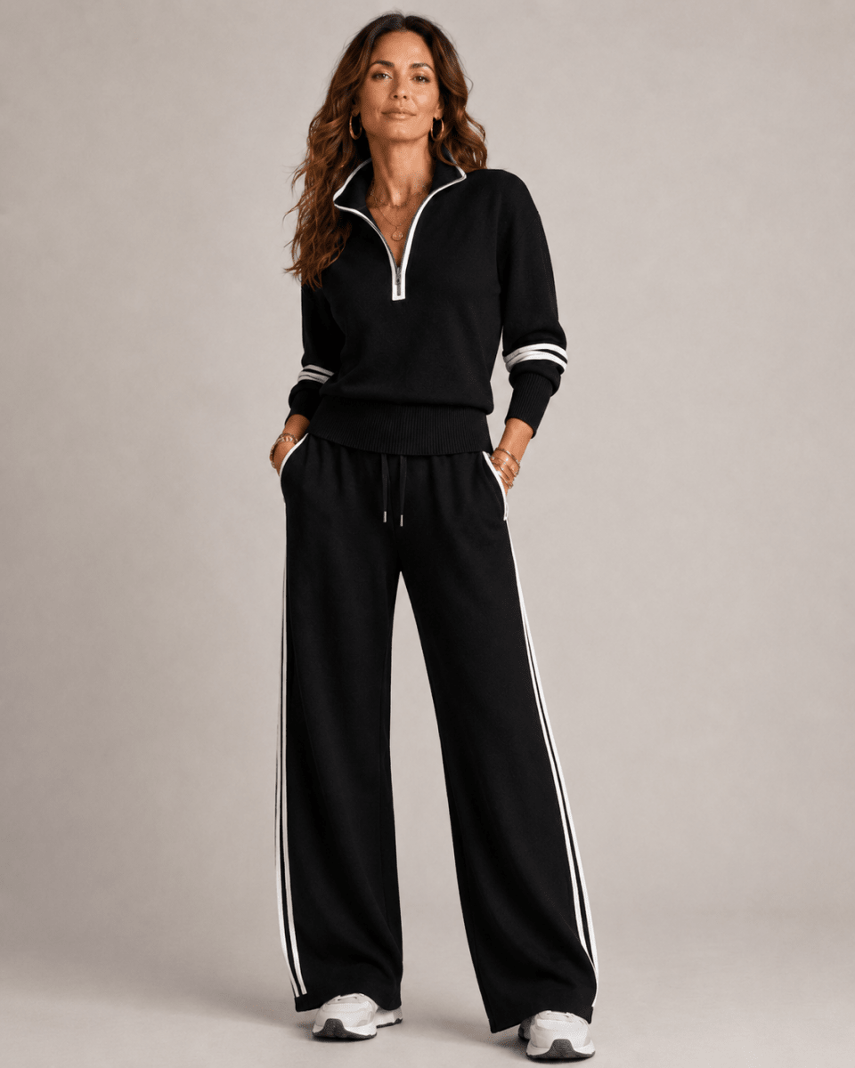 Woman wearing a black tracksuit with white stripes on a gray background