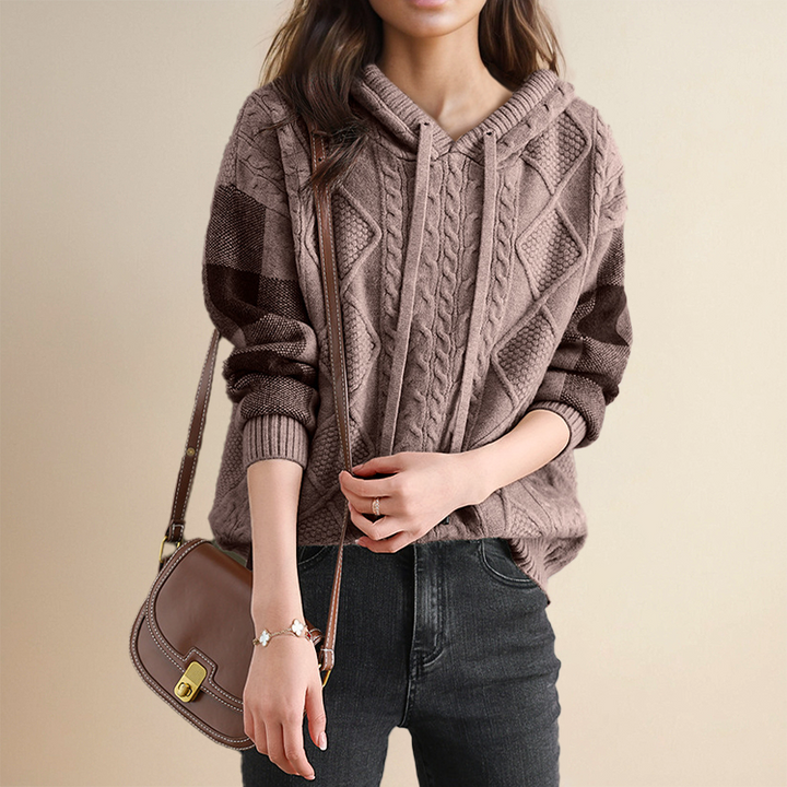 Person wearing a cable knit sweater with a plain background