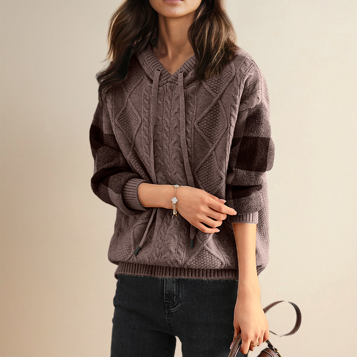 Person wearing a brown cable knit sweater against a beige background