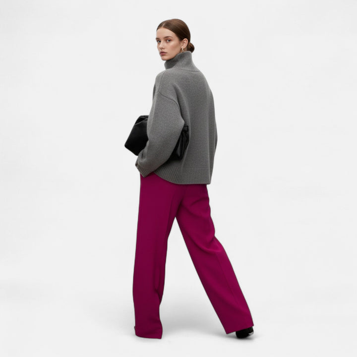 Woman wearing a gray sweater and magenta pants on a white background