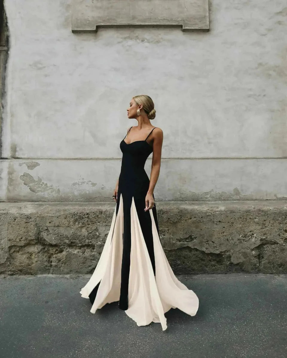 Woman in a black and white evening gown standing against a textured wall.