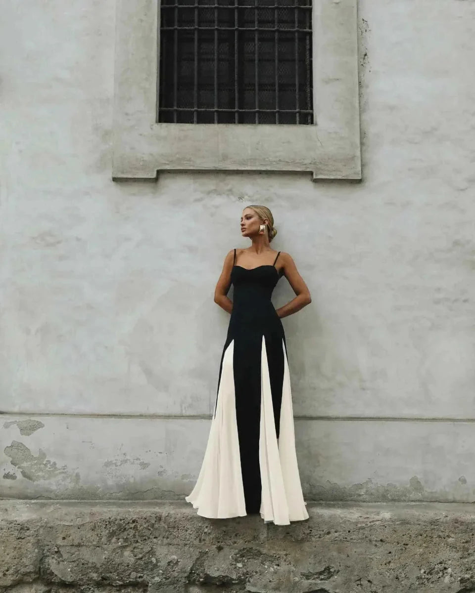 Woman in a black and white dress standing against a textured wall.