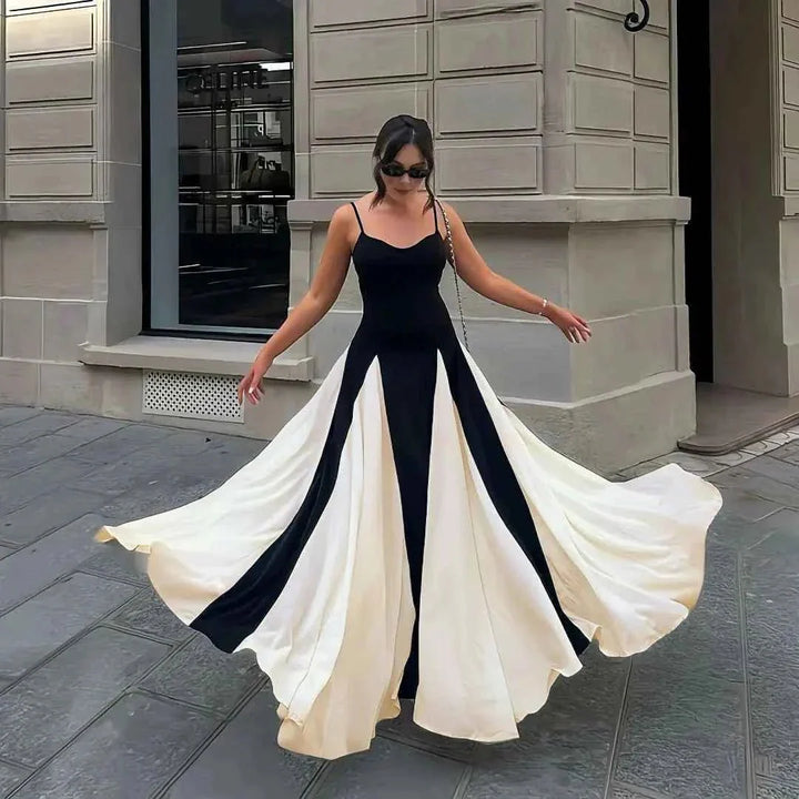 Woman in a black and white dress standing on a street.
