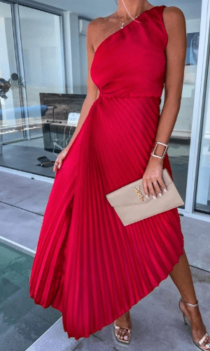Woman wearing a red one-shoulder dress holding a beige clutch.