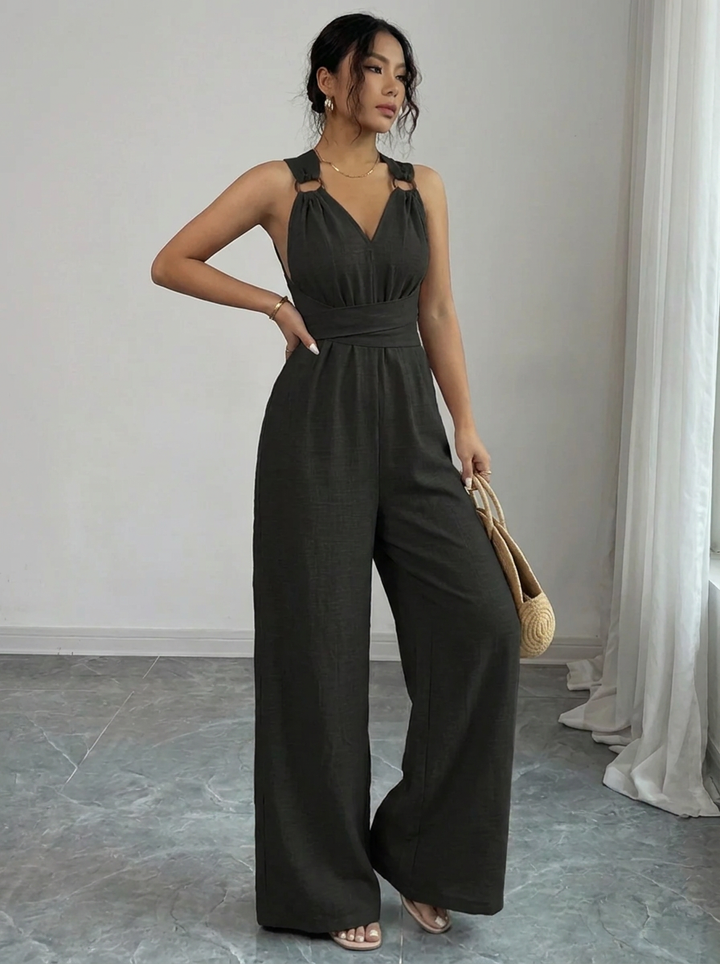 Woman wearing a dark green jumpsuit in a minimalistic room.