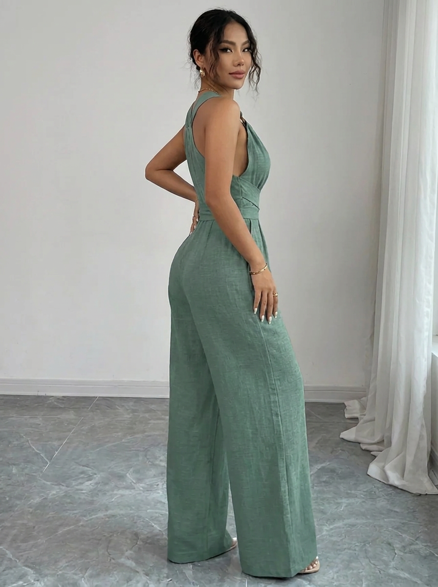 Woman wearing a green jumpsuit in a room with white curtains.