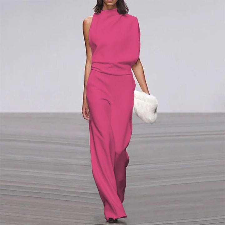 Model wearing a pink sleeveless jumpsuit on a gray runway.
