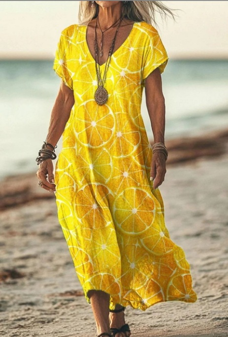 Woman wearing a yellow dress with a citrus pattern on a beach.