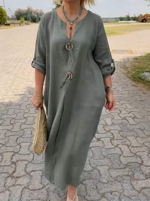 Person wearing a green dress with buttons on a paved path outdoors