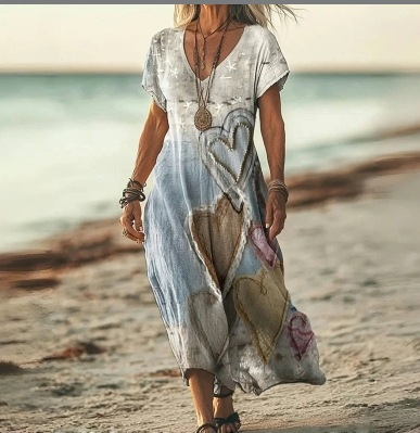 Woman in a floral dress walking on a beach with ocean in the background