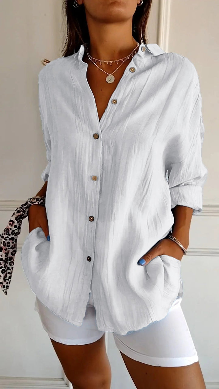 Person wearing a white button-up shirt and white shorts with a neutral background