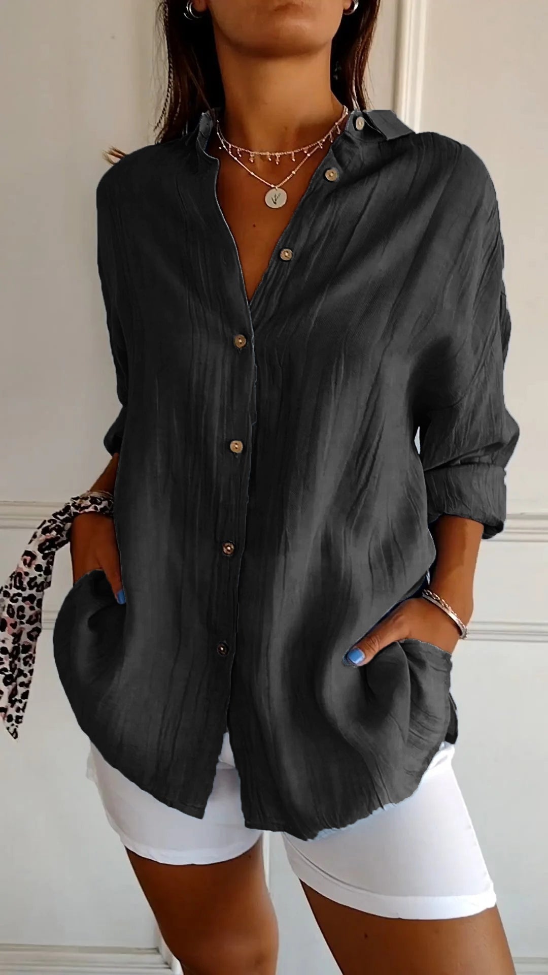 Person wearing a dark gray button-up shirt with rolled-up sleeves and white shorts.