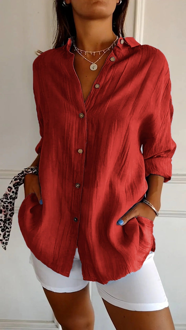 Person wearing a red button-up shirt and white shorts indoors.