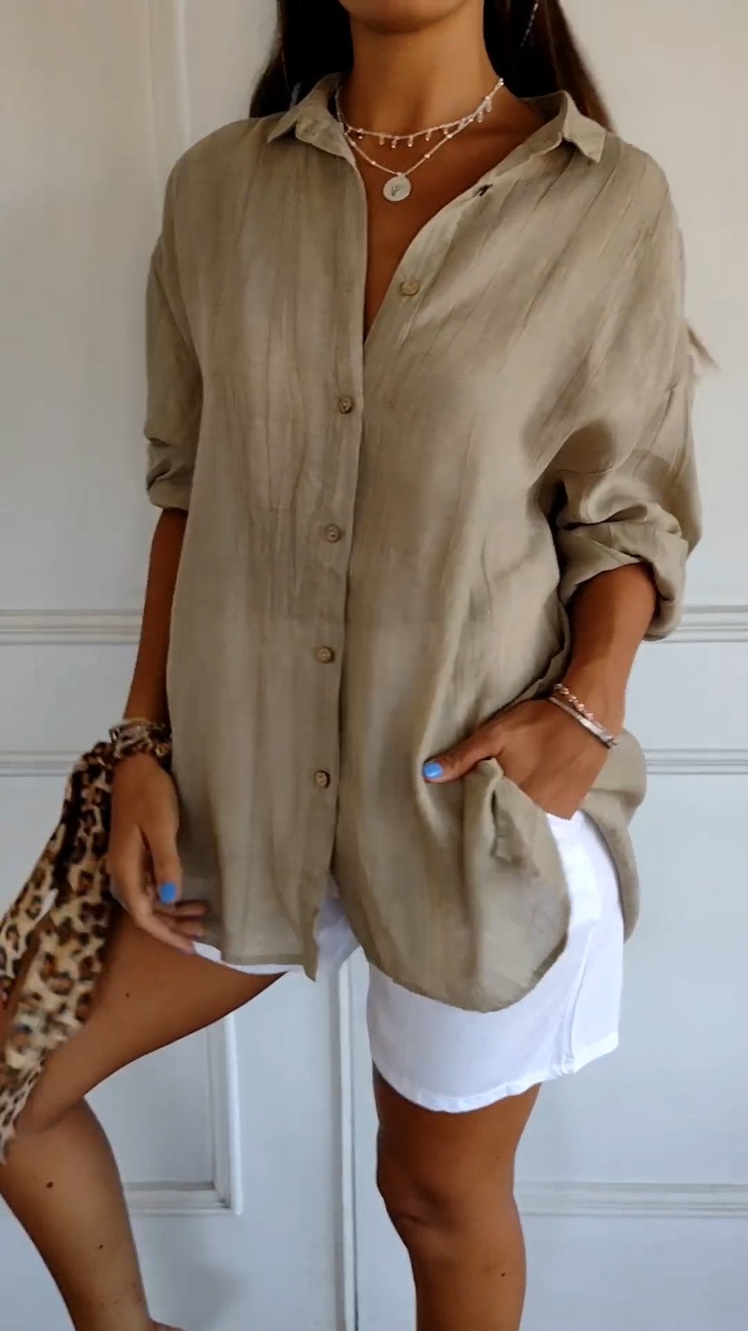 Woman wearing a beige button-up shirt and white shorts with a leopard print clutch.
