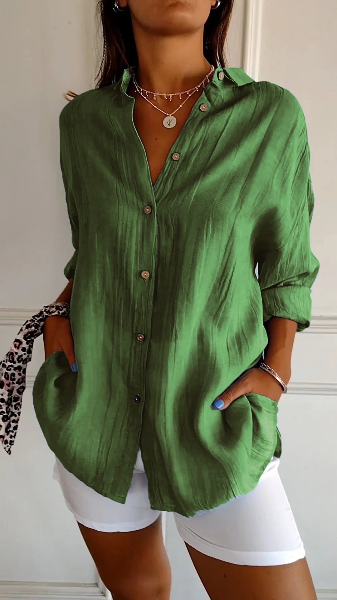 Person wearing a green button-up shirt and white shorts indoors.