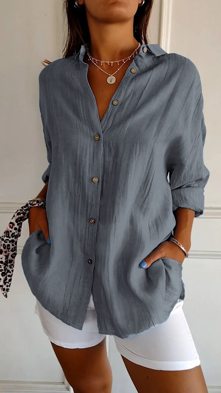 Woman wearing a blue button-up shirt and white shorts indoors.
